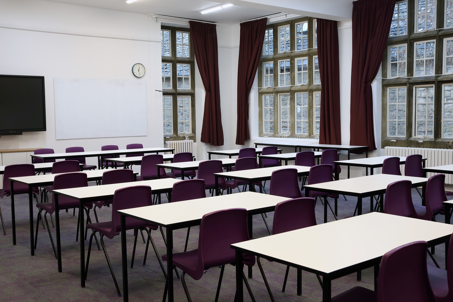 Christopher Cox room - a large room with windows all around filled with desks and 2 purple seats per desk